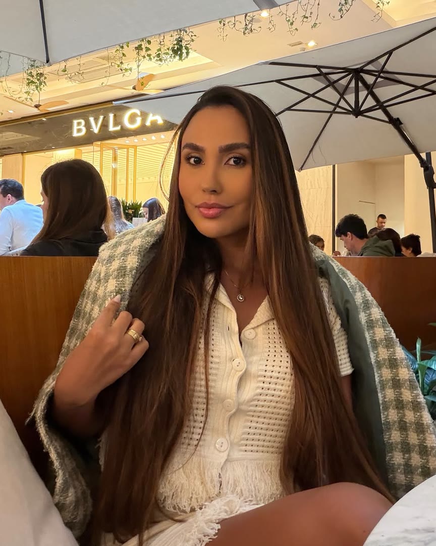 Dra. Letícia Menezes sentada num café, olhando para a câmera